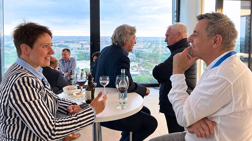 Close-up of a female and a male attendee discussing in front of the Munich panorama view during the evening event at The Automotive Battery – Key Technology for Electric Vehicles 9th - 10th July 2025